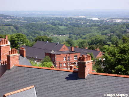 Picture of a red-brick school building seen across the roofs of houses