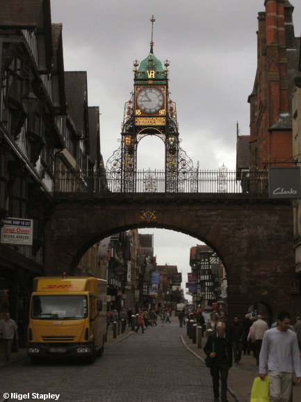 Picture of an ornate clock on a city wall crossing a street