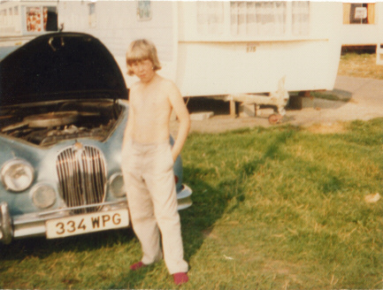 Picture of a boy standing in front of a Jaguar car