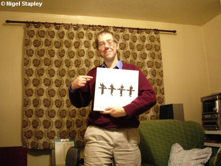 Photo of a man standing in his living room holding a Kraftwerk CD box set