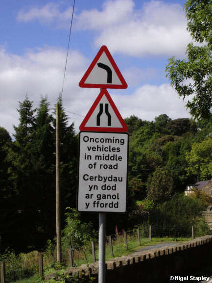 Photo of a road sign warning that oncoming traffic may be in the middle of the road