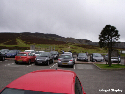 Photo across a small car park towards the spoil heaps of an old slate quarry